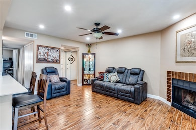 Living room with a tile fireplace, ceiling fan, and light hardwood / wood-style floors