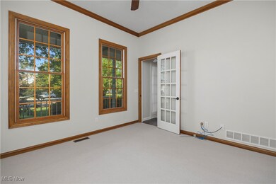 Carpeted empty room featuring crown molding, ceiling fan, and french doors