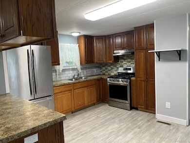 Kitchen featuring appliances with stainless steel finishes, backsplash, under cabinet range hood, and light wood-style flooring