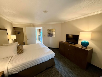 Bedroom with ornamental molding and a textured cei