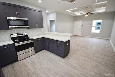 Kitchen featuring a peninsula, recessed lighting, coffered ceiling, a ceiling fan, and appliances with stainless steel finishes