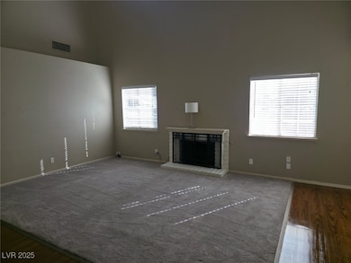 Unfurnished living room with plenty of natural light, dark wood-style flooring, and a high ceiling