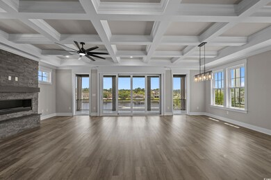 Unfurnished living room featuring a chandelier, a stone fireplace, a water view, ceiling fan, and dark wood-style floors