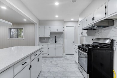 Kitchen with white cabinets, light stone counterto