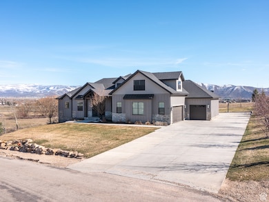Modern inspired farmhouse with a front lawn, a garage, a mountain view, stone siding, and board and batten siding