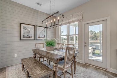 Dining space with light wood-style floors, visible vents, wooden walls, and baseboards