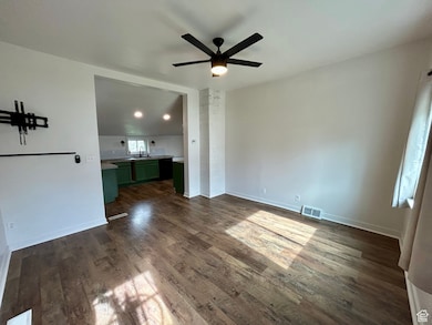 Unfurnished living room featuring dark wood finished floors and ceiling fan