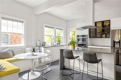 Kitchen with stainless steel double oven, modern cabinets, white cabinetry, a breakfast bar area, and a center island
