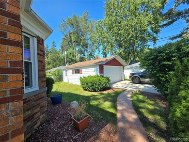 View of home's exterior featuring an outdoor structure, a yard, a detached garage, and brick siding