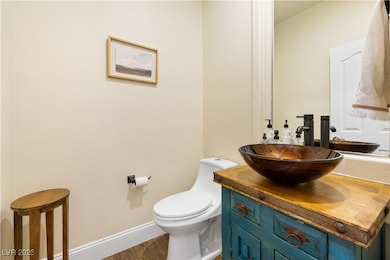 Bathroom with toilet, vanity, wood finished floors