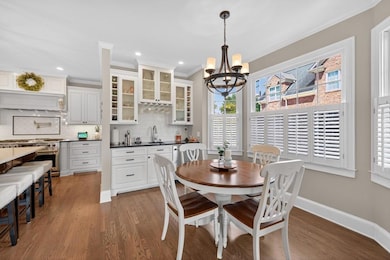 Dining area with a chandelier, wood finished floors, ornamental molding, wet bar, and recessed lighting