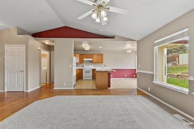 Kitchen featuring open floor plan, light countertops, vaulted ceiling, white appliances, and ceiling fan