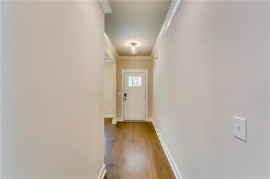 Doorway to outside featuring ornamental molding, wood-type flooring, and baseboards