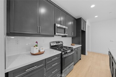 Modern kitchen with quartz countertops, subway tile backsplash, stainless steel appliances, and sleek dark cabinetry, paired with a nearby island that makes cooking, prepping, and entertaining effortless