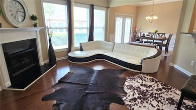 Living area featuring a chandelier, baseboards, wood finished floors, crown molding, and plenty of natural light