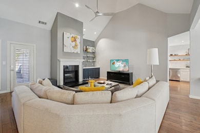 Living area featuring high vaulted ceiling, light wood-style floors, a glass covered fireplace, recessed lighting, and a ceiling fan