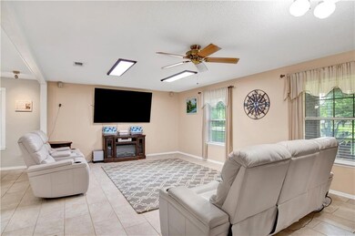 Living area with a ceiling fan, baseboards, and light tile patterned floors