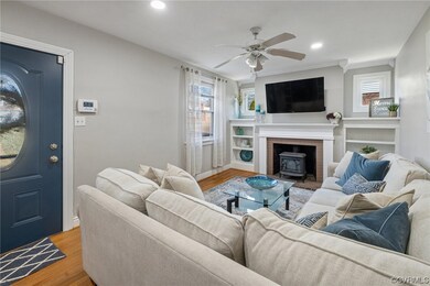 Living room featuring a wood stove, a brick fireplace, hardwood  floors, and ceiling fan