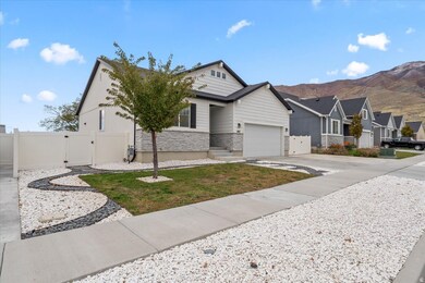 View of front of property featuring stone siding, a gate, driveway, landscaped yard