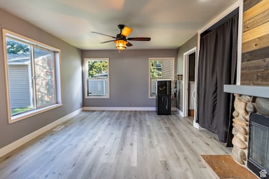 Unfurnished living room featuring a fireplace, light wood-type flooring, and a ceiling fan
