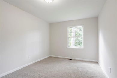 Carpeted spare room featuring baseboards