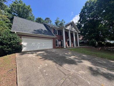Neoclassical / greek revival house with driveway, an attached garage, and brick siding