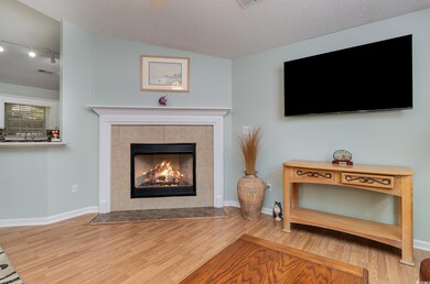 Living room featuring baseboards, track lighting, visible vents, a tile fireplace, and wood finished floors