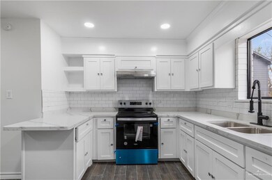 Kitchen featuring a sink, under cabinet range hood, electric stove, white cabinets, and open shelves