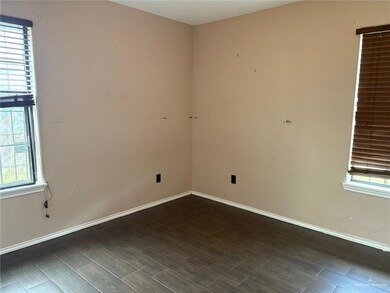 Empty room with healthy amount of natural light, dark wood-style floors, and baseboards