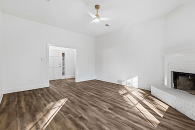 Unfurnished living room with dark wood finished floors, a fireplace, and a ceiling fan