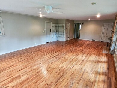 Hardwood floored living room with ornamental molding, a fireplace, and ceiling fan