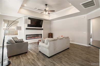 Living room featuring a tray ceiling, ceiling fan,