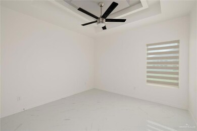 Spare room featuring marble finish flooring, a tray ceiling, baseboards, and a ceiling fan