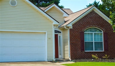 Ranch-style house with a garage, brick siding, concrete driveway, and roof with shingles