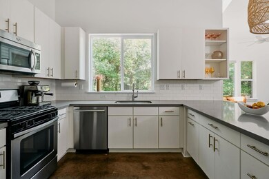 Kitchen with stainless steel appliances, finished concrete floors, a sink, open shelves, and tasteful backsplash