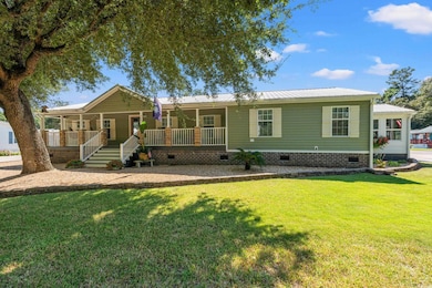 View of front facade featuring crawl space, covered porch, a metal roof, and a front lawn