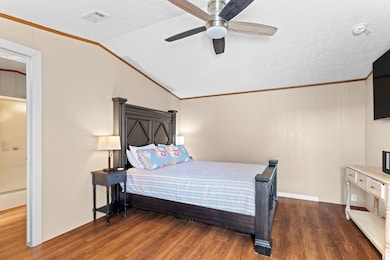 Bedroom featuring ornamental molding, a textured ceiling, dark wood-style flooring, lofted ceiling, and a ceiling fan