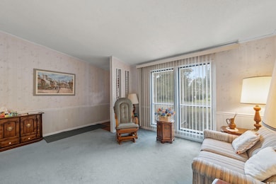 Sitting room featuring wallpapered walls, a wainscoted wall, a textured ceiling, and carpet