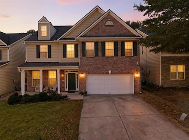 View of front facade with a porch, driveway, brick siding, a garage, and a front yard