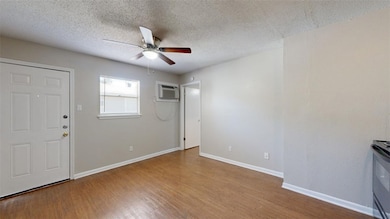 Entryway with a textured ceiling, light wood finished floors, a ceiling fan, and an AC wall unit
