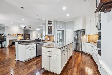 Island kitchen has wood floors, stainless steel ap