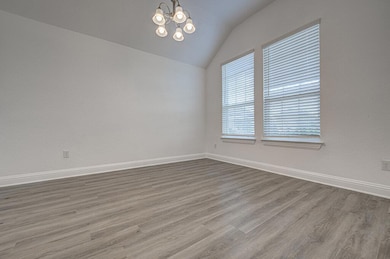 Spare room with vaulted ceiling, a chandelier, an