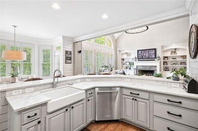 Kitchen featuring dishwasher, a sink, open floor plan, light stone countertops, and lofted ceiling