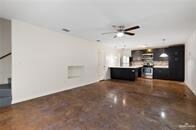 Unfurnished living room featuring a ceiling fan and baseboards