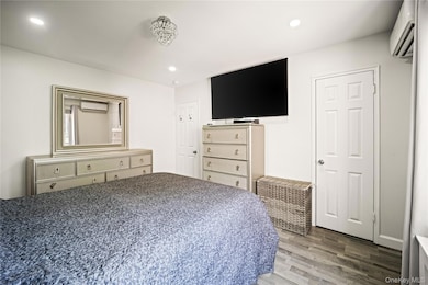 Bedroom with light wood finished floors, recessed lighting, and a wall mounted AC