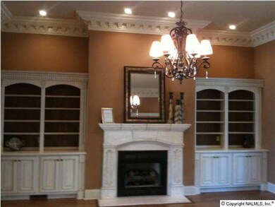 Great room features custom built-in bookshelves, exquisite dental crown molding, gas-log fireplace, beautiful hardwood, long windows, and French doors leading out to a beautiful covered back porch.