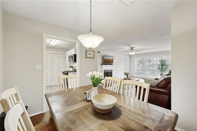 Dining area with a fireplace, ceiling fan, baseboards, and dark wood-style floors
