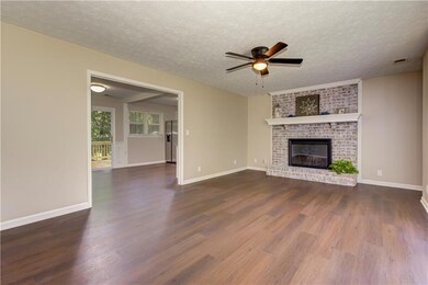 Unfurnished living room with dark wood finished floors, a ceiling fan, a fireplace, and a textured ceiling