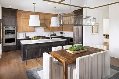 Kitchen featuring stainless steel appliances, recessed lighting, a kitchen breakfast bar, hanging light fixtures, warm wood finished floors, and casual dining area. Photo is representative of the Acworth Model Home. Designer features will vary.