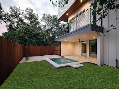 Fenced backyard featuring a balcony, a patio area, and an in-ground hot tub